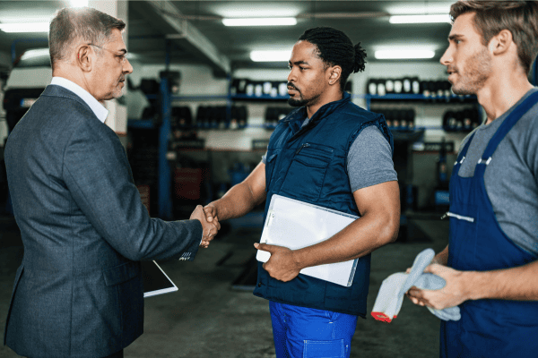 Automotive manager shaking hands with a mechanic, symbolizing a partnership in power battery solutions.