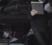 Man using a digital tablet while charging an electric car, symbolizing advanced power battery solutions